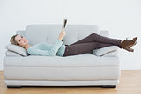 Content casual woman holding newspaper lying on couch