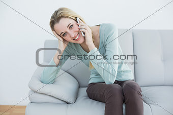 Lovely casual woman phoning while sitting on couch