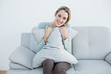 Pretty casual woman sitting on couch holding smiling a pillow