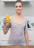 Smiling gorgeous model looking at camera holding orange juice