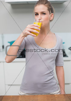 Calm gorgeous model looking at camera drinking orange juice