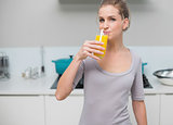Peaceful gorgeous model looking at camera drinking orange juice
