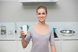 Smiling gorgeous model looking at camera holding glass of milk
