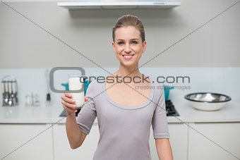 Smiling gorgeous model looking at camera holding glass of milk