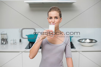 Calm gorgeous model looking at camera drinking glass of milk