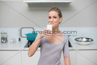 Smiling gorgeous model looking at camera drinking glass of milk
