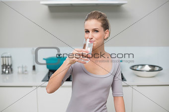 Happy gorgeous model looking at camera drinking glass of milk