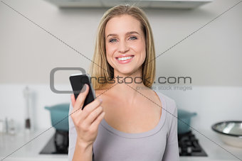 Cheerful gorgeous model holding smartphone looking at camera