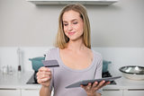Smiling gorgeous model holding tablet and credit card