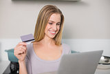 Cheerful gorgeous model holding laptop and credit card