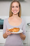 Cheerful gorgeous model holding plate with croissant
