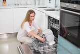 Happy gorgeous model kneeling behind dish washer