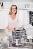 Cheerful gorgeous model kneeling behind dish washer