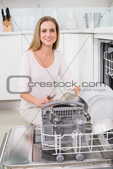 Cheerful gorgeous model kneeling behind dish washer
