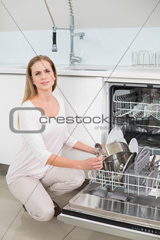 Frowning gorgeous model kneeling next to dish washer