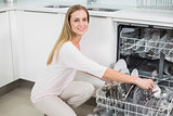 Smiling gorgeous model kneeling next to dish washer