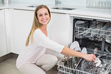 Cheerful gorgeous model kneeling next to dish washer