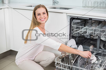 Cheerful gorgeous model kneeling next to dish washer