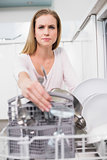 Frowning gorgeous model kneeling behind dish washer