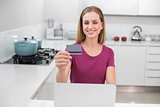 Laughing casual woman using laptop and credit card