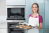 Casual happy woman holding baking tray with cookies