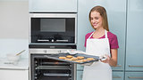 Casual blonde woman holding baking tray with cookies