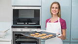 Casual content woman holding baking tray with cookies