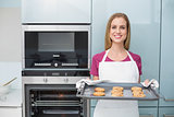 Casual attractive woman holding baking tray with cookies