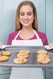 Casual happy woman looking at baking tray with cookies
