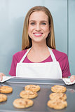 Casual happy woman showing baking tray with cookies