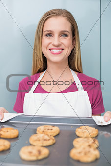 Casual happy woman showing baking tray with cookies