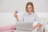 Content casual blonde relaxing on couch doing online shopping