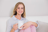 Happy casual blonde sitting on couch holding mug