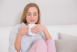 Peaceful casual blonde sitting on couch holding mug