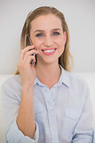 Smiling casual blonde phoning with smartphone