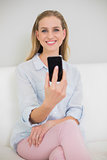 Smiling casual blonde holding smartphone