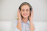 Smiling casual blonde listening to music with closed eyes