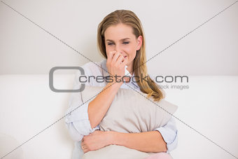 Upset casual blonde sitting on couch crying