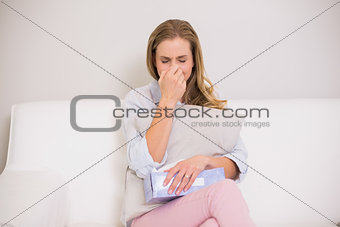 Unhappy casual blonde sitting on couch crying