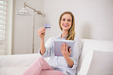 Laughing casual blonde using tablet for online shopping