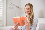 Smiling casual blonde sitting on couch reading