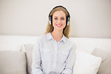 Smiling casual blonde sitting on couch with headphones