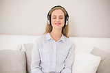 Happy casual blonde sitting on couch with headphones