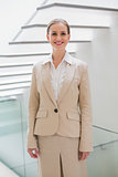 Smiling stylish businesswoman standing next to stairs