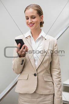 Smiling stylish businesswoman holding smartphone