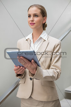 Pensive stylish businesswoman holding tablet