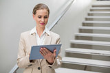 Thoughtful stylish businesswoman looking at tablet