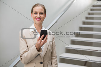 Laughing stylish businesswoman holding smartphone