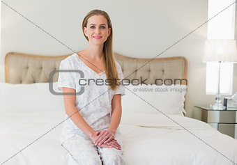 Natural happy woman sitting on bed