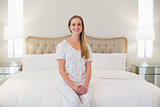 Natural cheerful woman sitting on bed